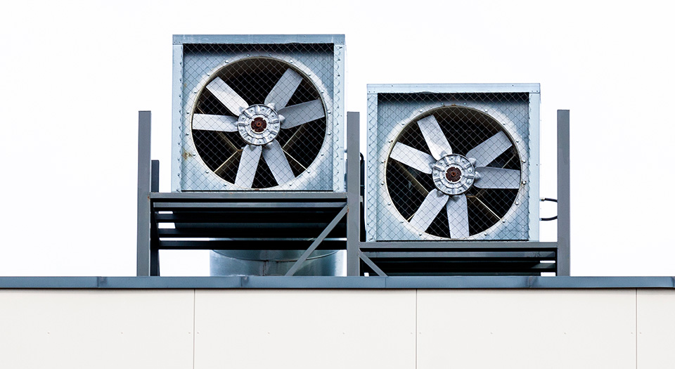 Dois exaustores industriais no telhado de um prédio.